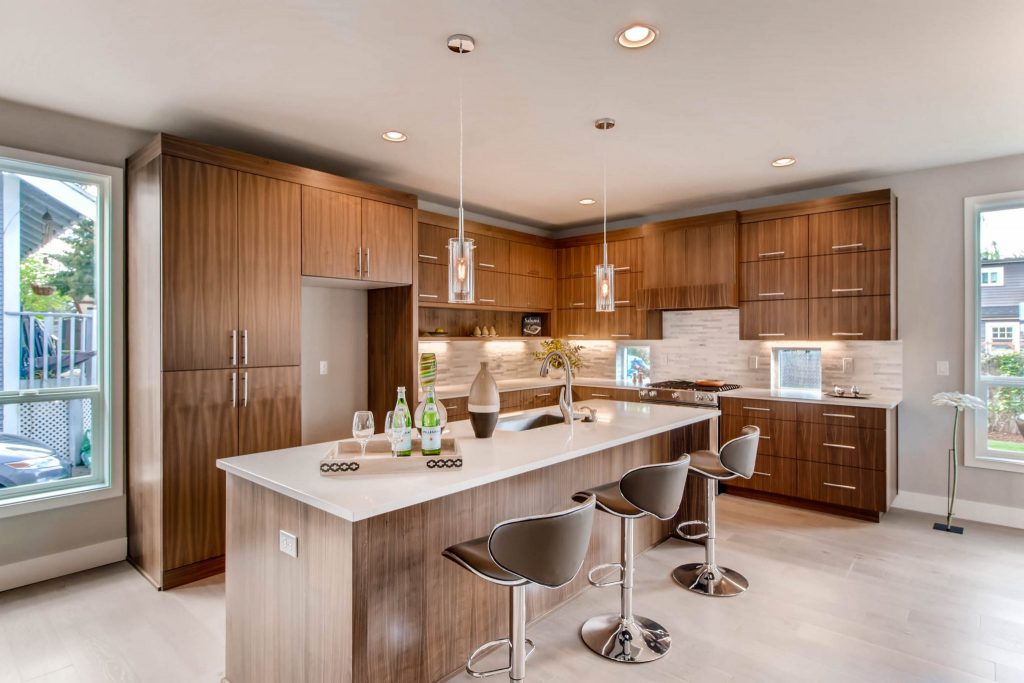 Modern kitchen remodel with light wood floors, wood cabinetry, and stainless steel fixtures in a luxury home remodel