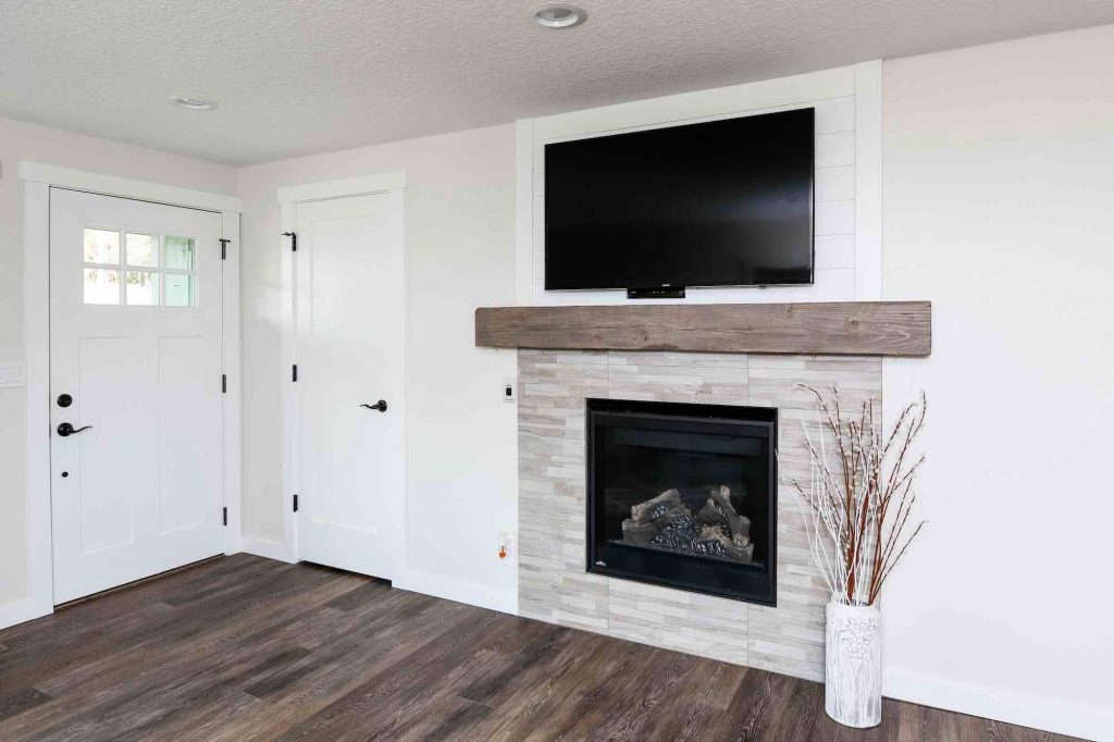 Living room with weathered wood floors, tile inset fireplace, and weathered wood mantle in a recently remodeled home
