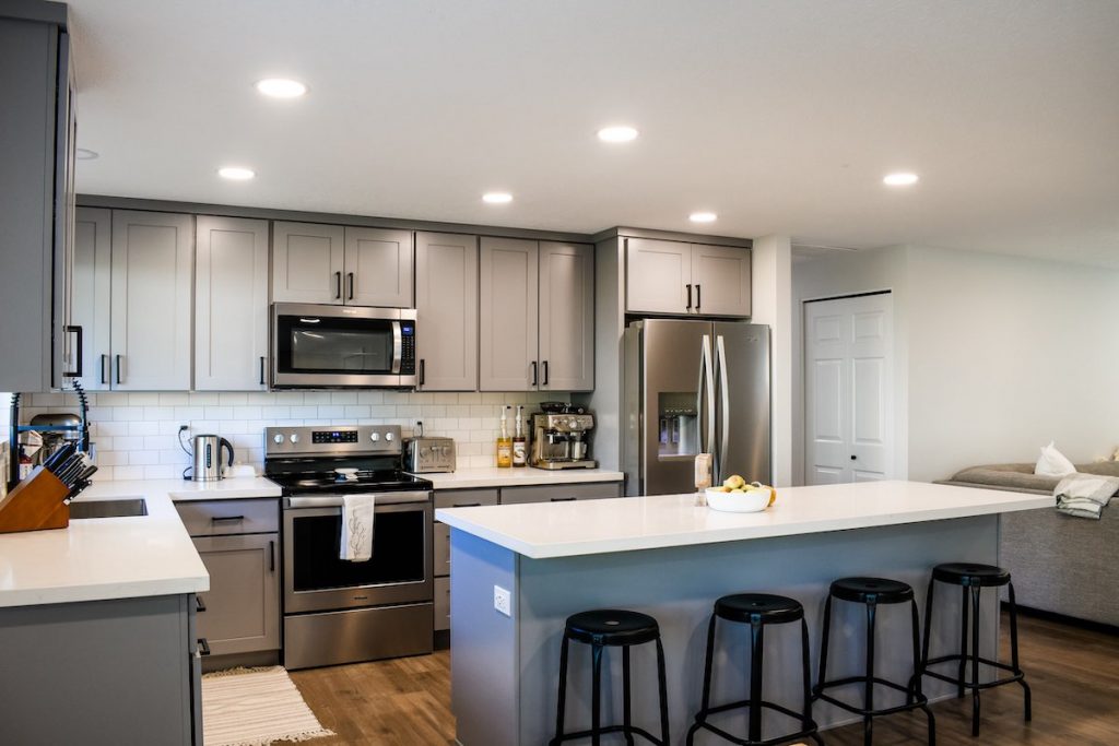 Kitchen remodel featuring stainless steel appliances, custom gray cabinetry, and white marble counters