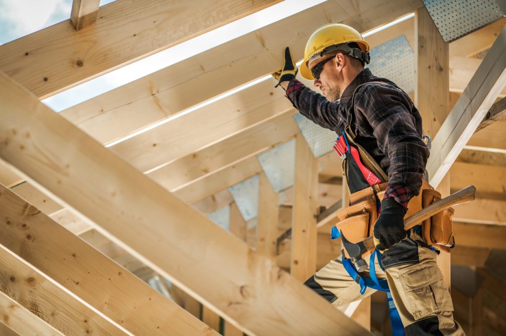caucasian male construction worker holding a hammer doing home construction