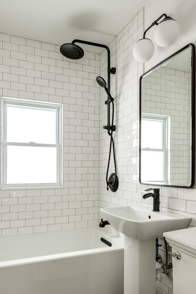 bathtub with white rectangular tiles and black fixture